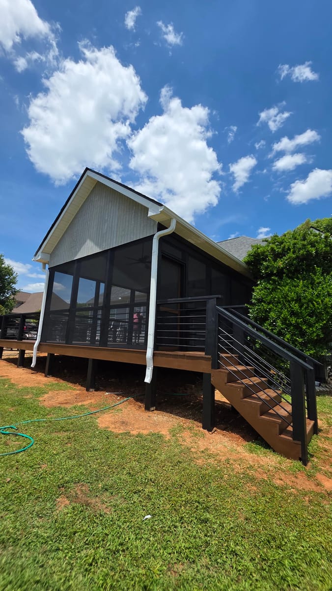Deck extended and enclosed as a screened porch under a new gable roof, with horizontal metal railings and stained stairs, Adairsville, Georgia