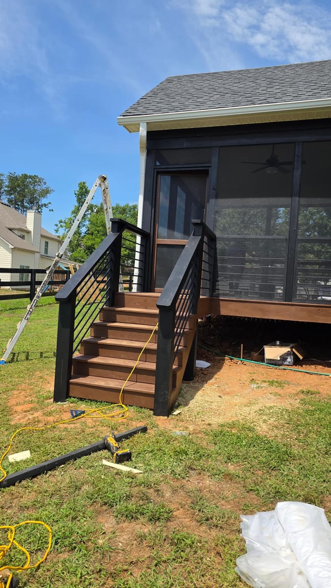 Deck extended and enclosed as a screened porch under a new gable roof, with horizontal metal railings and stained stairs, Adairsville, Georgia