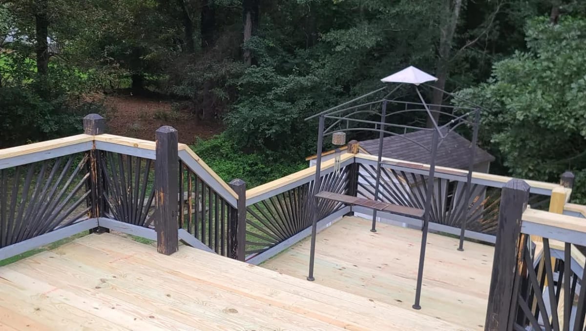 New decking boards laid over the existing frame of a large elevated deck; decorative black sunburst railing panels retained, Atlanta, Georgia