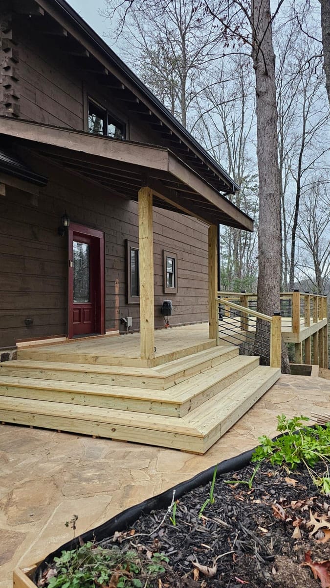 Wide entry steps and landing in fresh timber, with cable railing, meeting the flagstone path at a cabin door, Blue Ridge, Georgia
