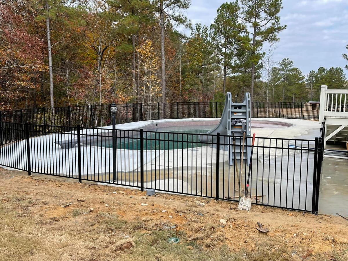 Black wrought-iron style pool enclosure fence set on a graded slope, Dallas, Georgia