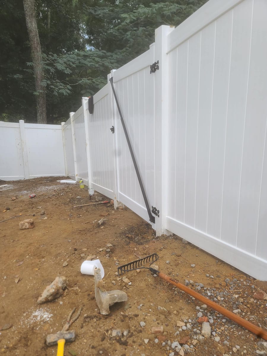 White vinyl privacy fence with braced gate, enclosing a wooded rear garden, Dalton, Georgia