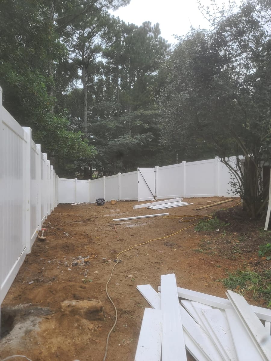 White vinyl privacy fence with braced gate, enclosing a wooded rear garden, Dalton, Georgia