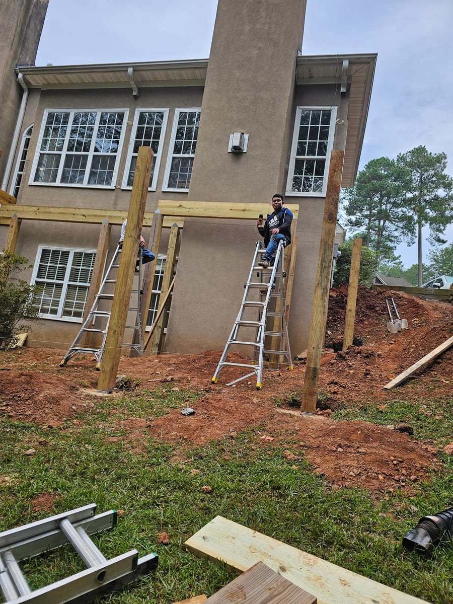 Deck framing under way on a stucco home: posts set, beams and joists going in, McDonough, Georgia