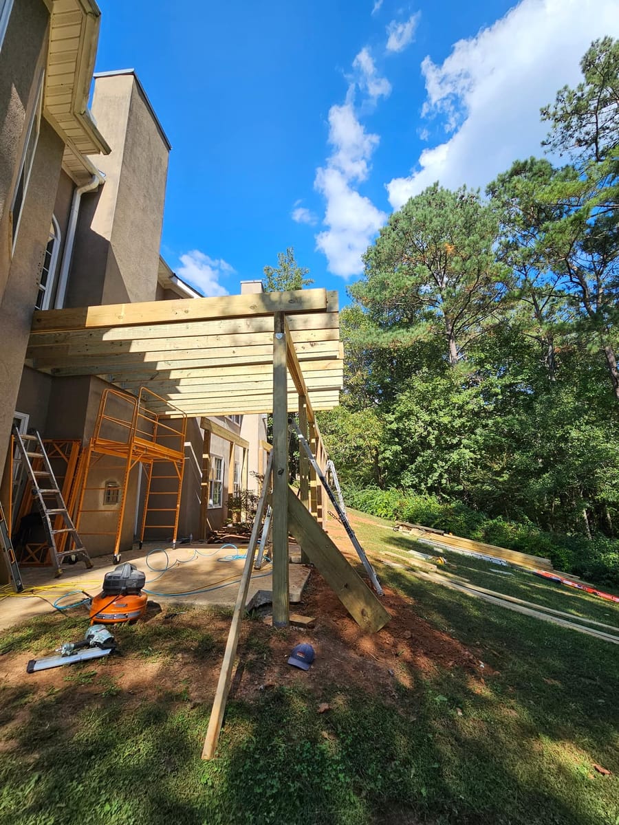 Deck framing under way on a stucco home: posts set, beams and joists going in, McDonough, Georgia