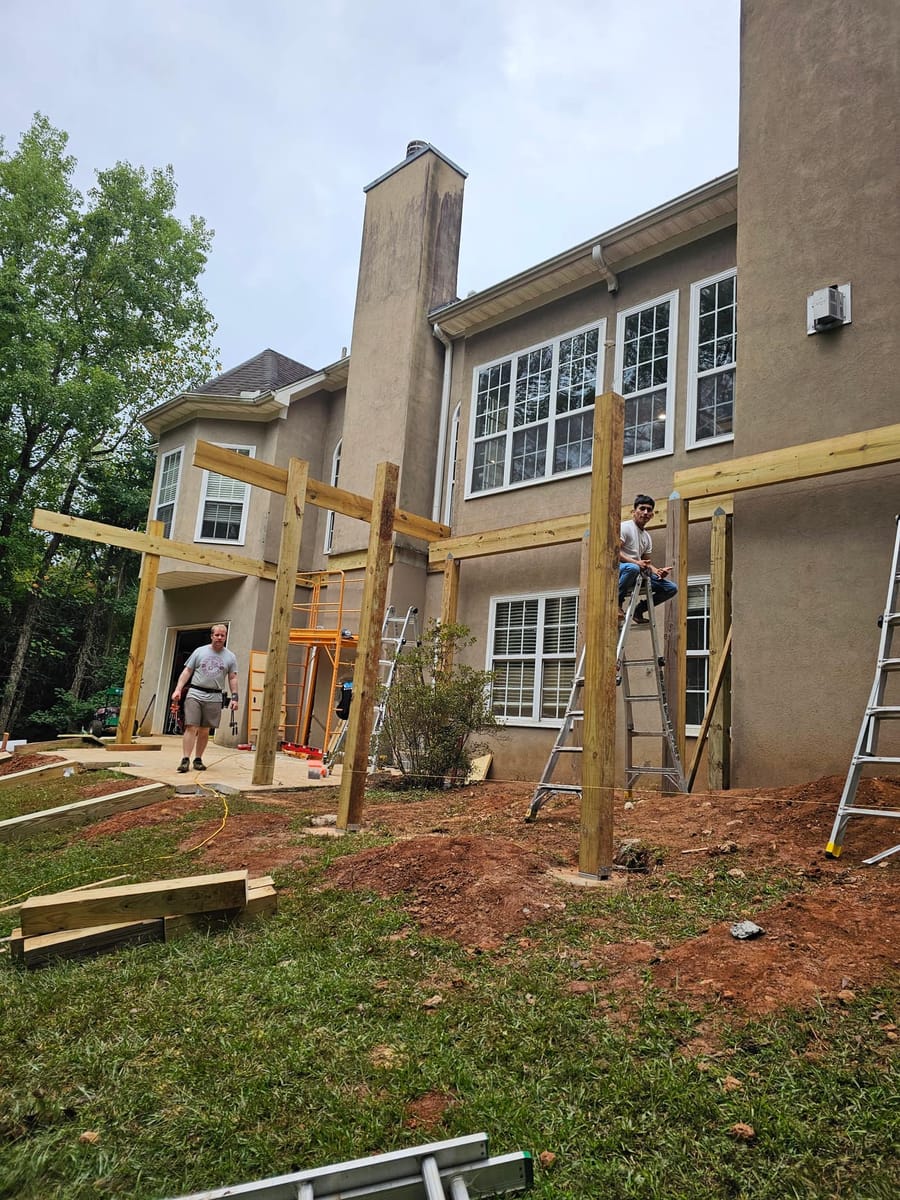 Deck framing under way on a stucco home: posts set, beams and joists going in, McDonough, Georgia