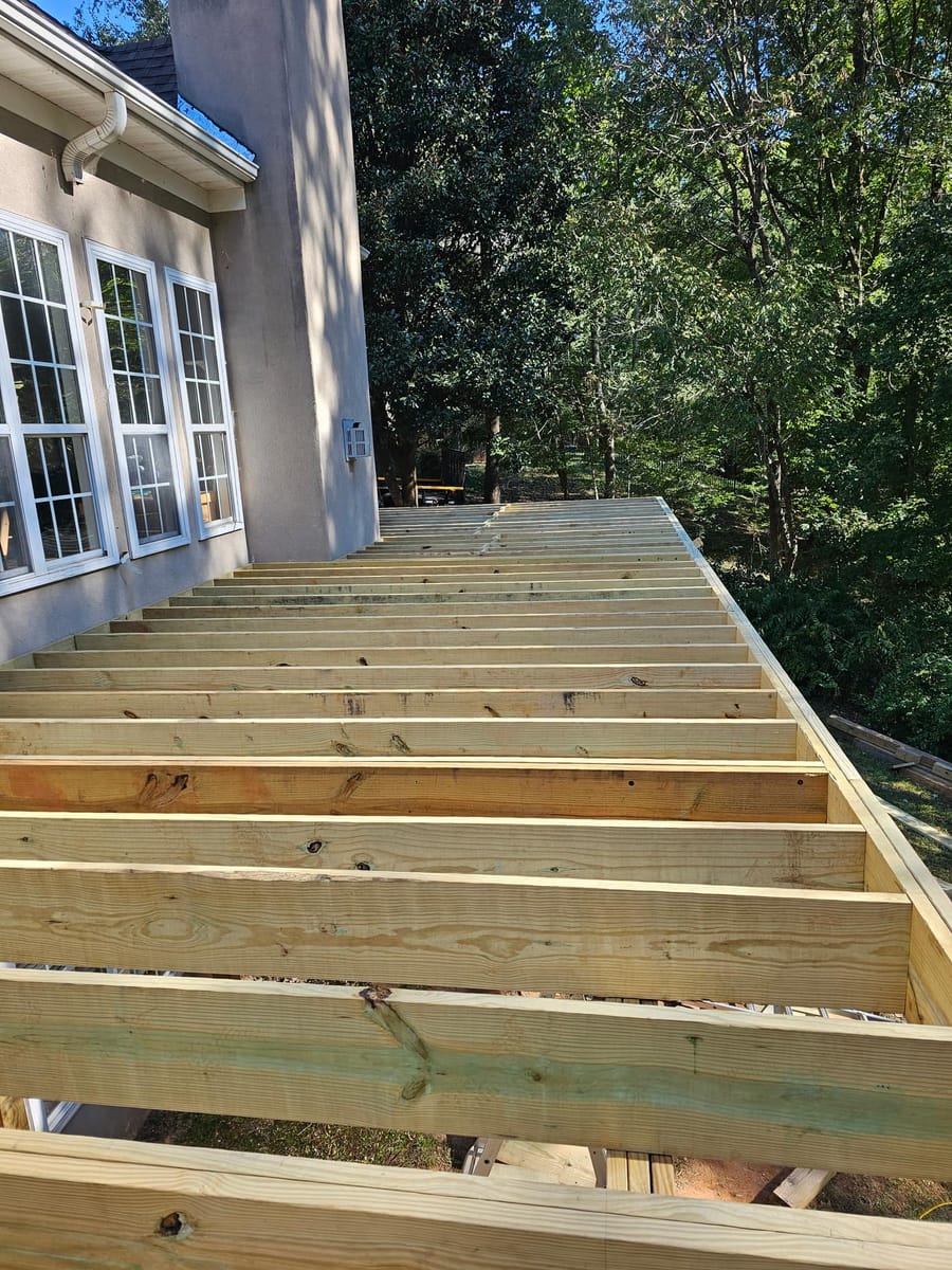 Deck framing under way on a stucco home: posts set, beams and joists going in, McDonough, Georgia