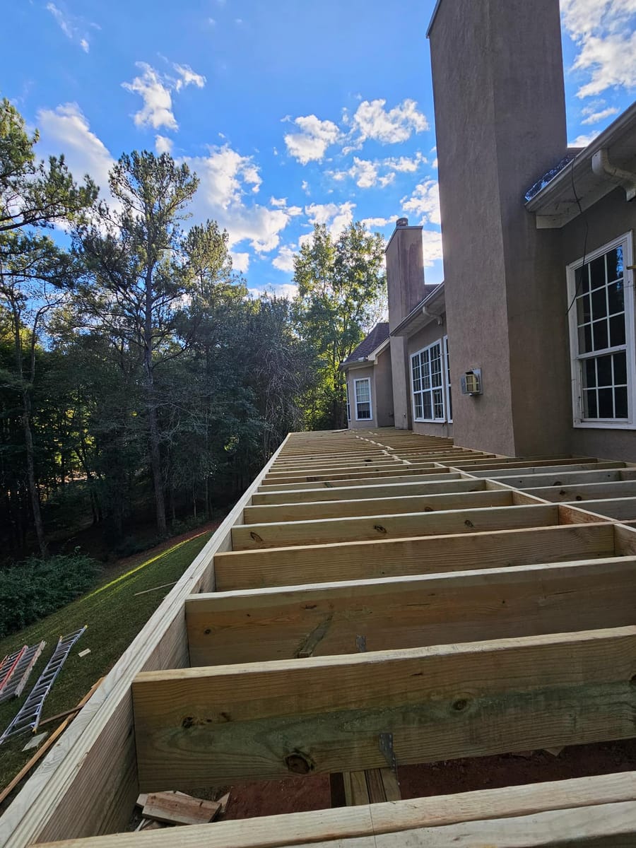 Deck framing under way on a stucco home: posts set, beams and joists going in, McDonough, Georgia