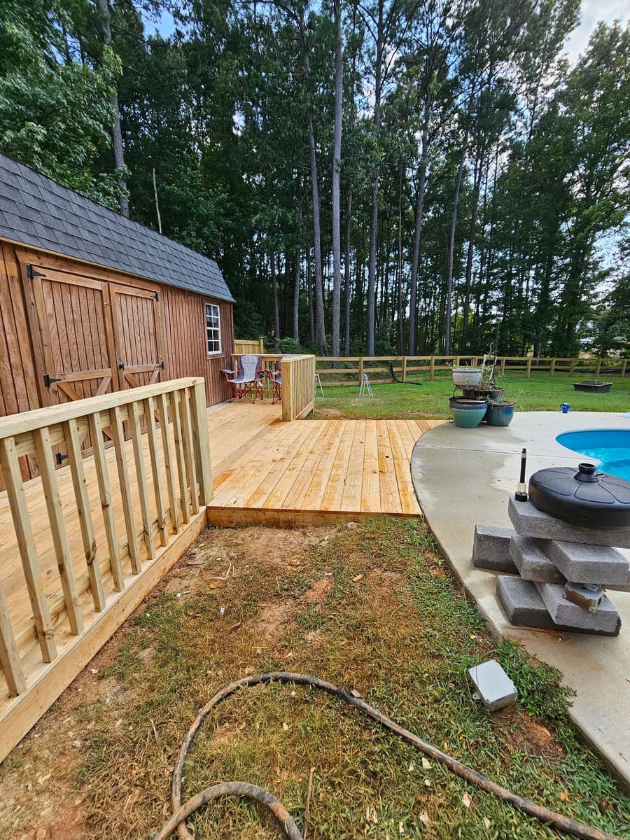 Timber pool deck framed and boarded around an above-ground pool beside a barn, Rome, Georgia