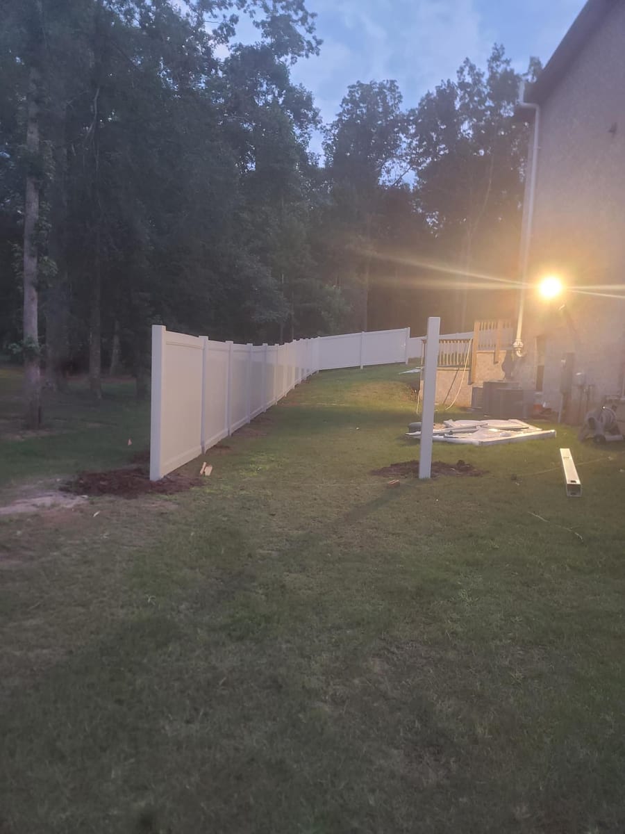 Tan vinyl privacy fence installed across a wooded residential boundary, Stockbridge, Georgia