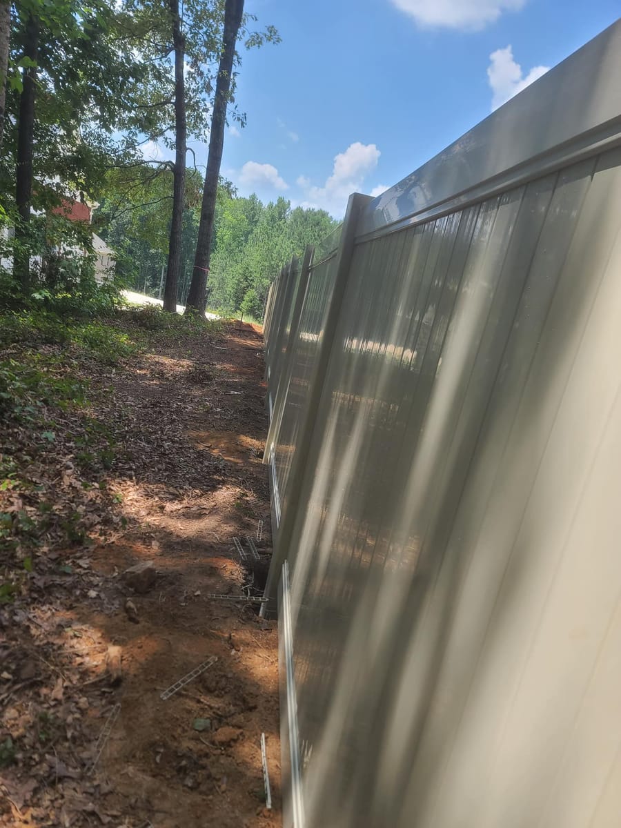 Tan vinyl privacy fence installed across a wooded residential boundary, Stockbridge, Georgia