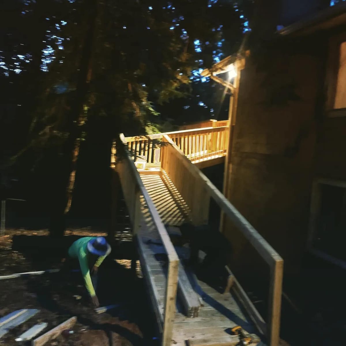 Long switchback accessibility ramp in pressure-treated lumber with full-height railings, rising through wooded ground to an elevated rear entry, Woodstock, Georgia