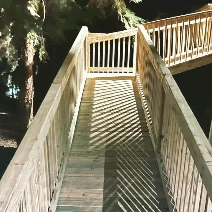 Long switchback accessibility ramp in pressure-treated lumber with full-height railings, rising through wooded ground to an elevated rear entry, Woodstock, Georgia