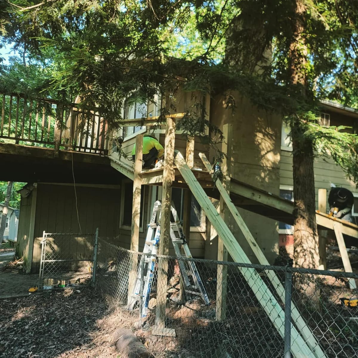 Long switchback accessibility ramp in pressure-treated lumber with full-height railings, rising through wooded ground to an elevated rear entry, Woodstock, Georgia