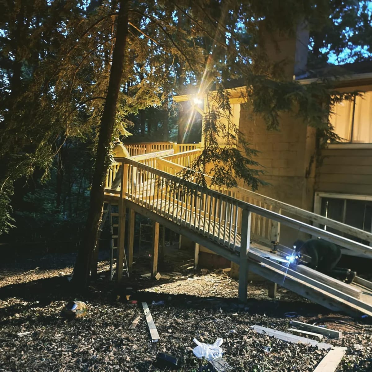Long switchback accessibility ramp in pressure-treated lumber with full-height railings, rising through wooded ground to an elevated rear entry, Woodstock, Georgia